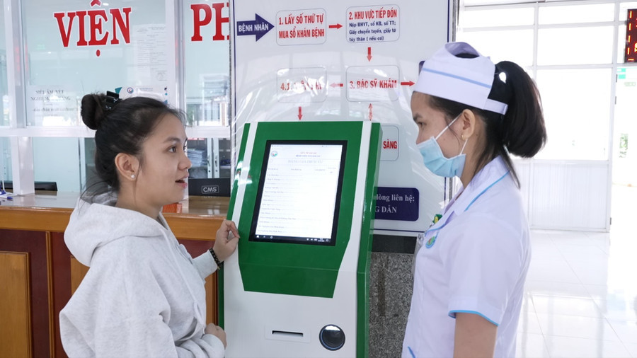 Nhân viên y tế Bệnh viện Nhi Gia Lai hướng dẫn người dân đăng ký khám, chữa bệnh trên Kiosk y tế thông minh (Ảnh: Báo Gia Lai)