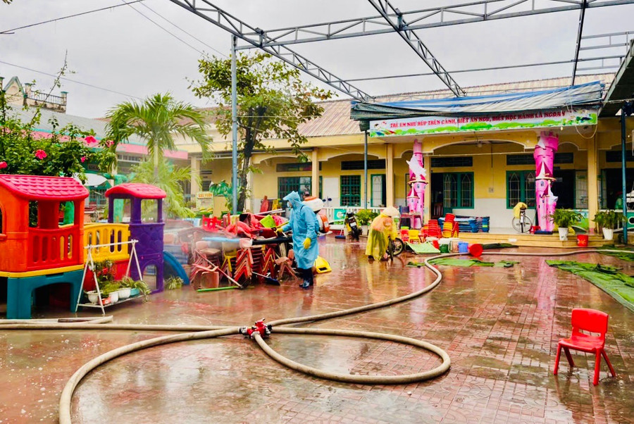 Nhân viên y tế phun thuốc khử khuẩn môi trường tại trường học ở phường Quy Nhơn Bắc sau ngập lụt (Ảnh: M.N)